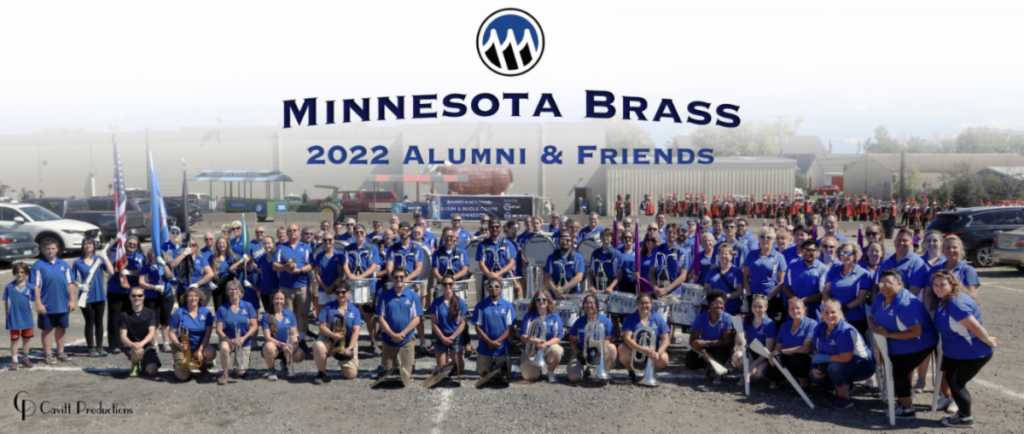 alumni-parade - MBI Arts Group photo of Minnesota Brass alumni and friends in blue shirts with instruments, outdoors at a reunion event.