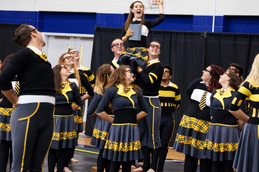 MBI Winter Guard members in bee costumes lifting a performer during the 2017 show The Bee